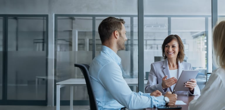 Team mature ceo businesswoman mentor discussing project with young european colleagues on tablet sitting in office. Professional business people working together using technology