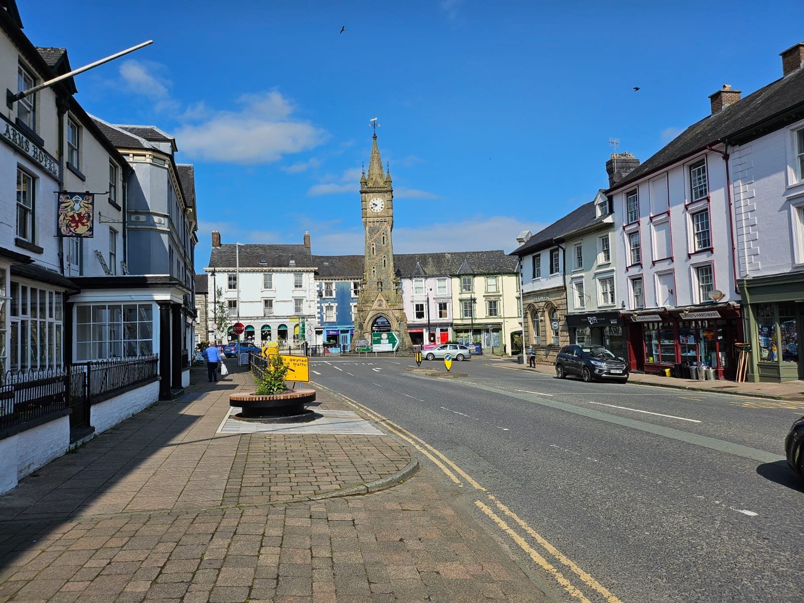 Historic town square with clock tower, period buildings, and clear blue sky in a charming British village