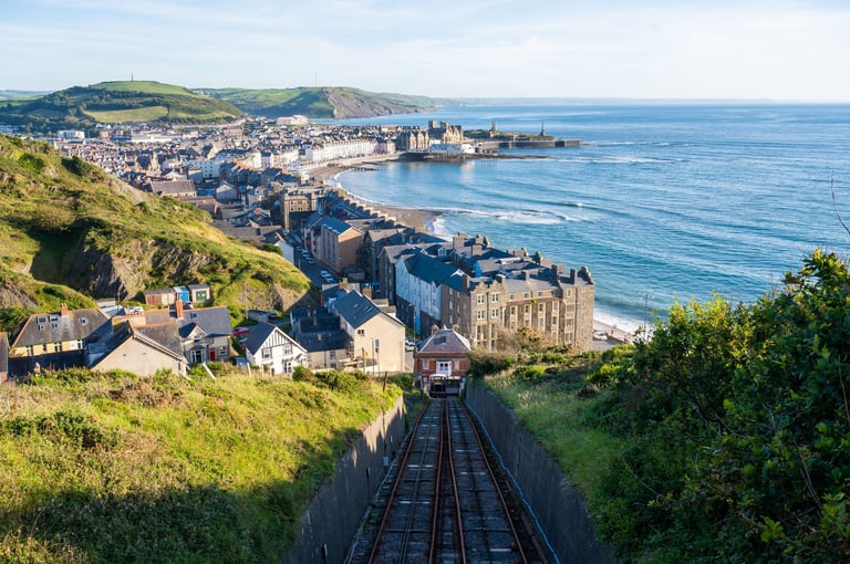 Elevated view of coastal town with railway tracks descending toward the sea and beachfront buildings below